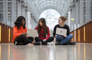 drie studenten zitten achter laptop