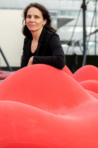 Ana Verbanescu leunend op een rood kunstwerk buiten