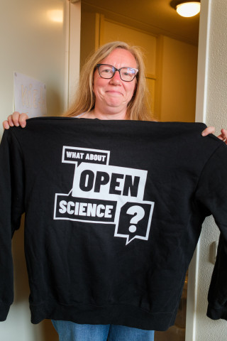 Sarah Coombs houdt een trui omhoog met de tekst: what about open science?