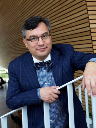 Foto van een man in pak met vlinderdas en bril op een trap