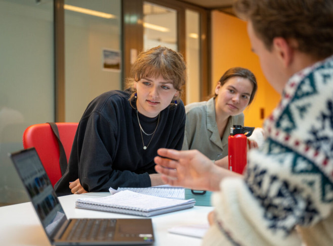 studente buigt voorover en kijkt op de laptop van een medestudent