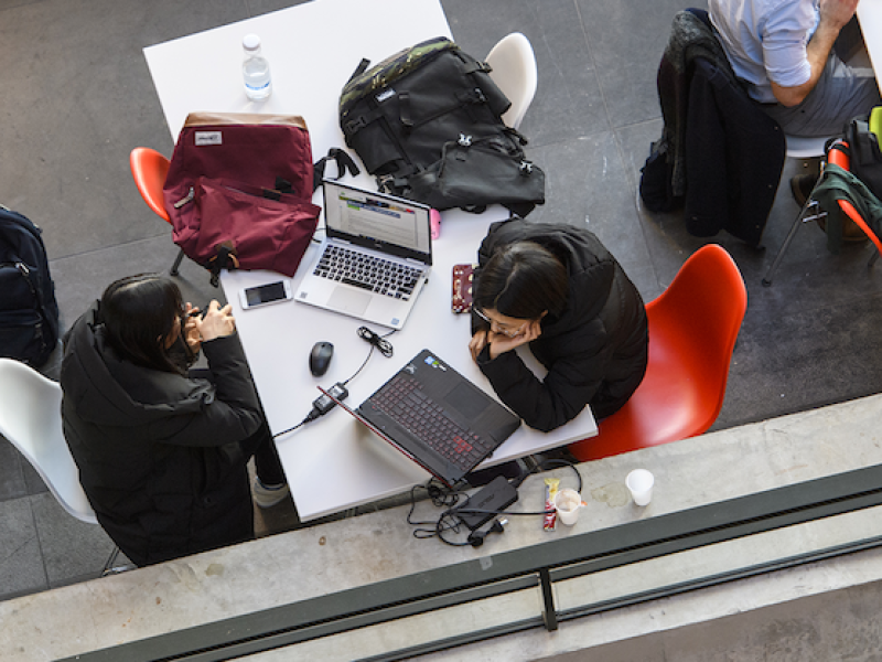 Bovenaanzicht van studenten achter computer met mobiel