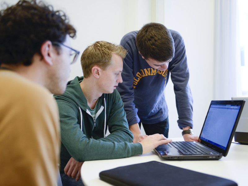 Drie studenten achter een laptop