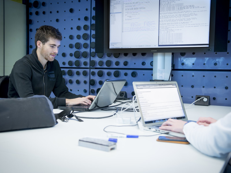 Mannen achter laptop en groot scherm