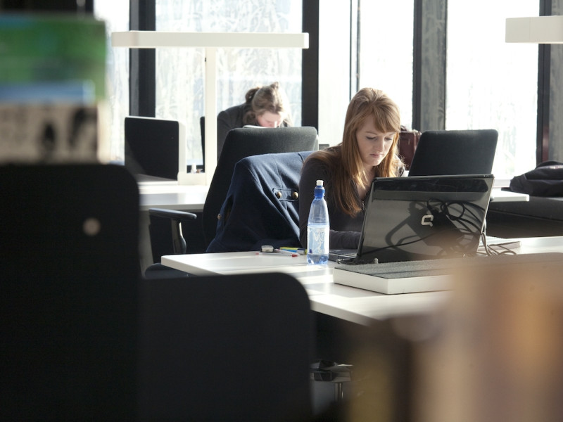 Studente in bibliotheek met computer online 