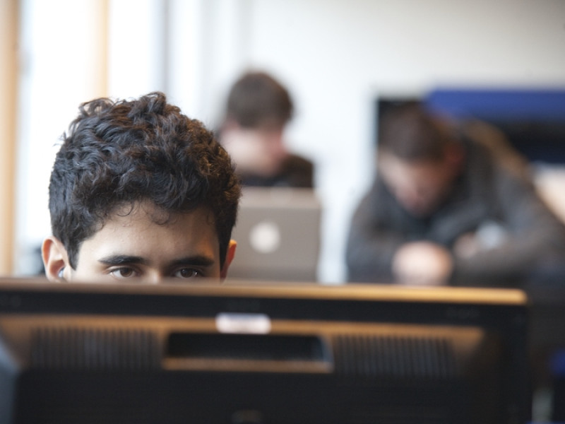 Jongen achter computer te zien waarbij zijn ogen net boven het scherm uitkomen