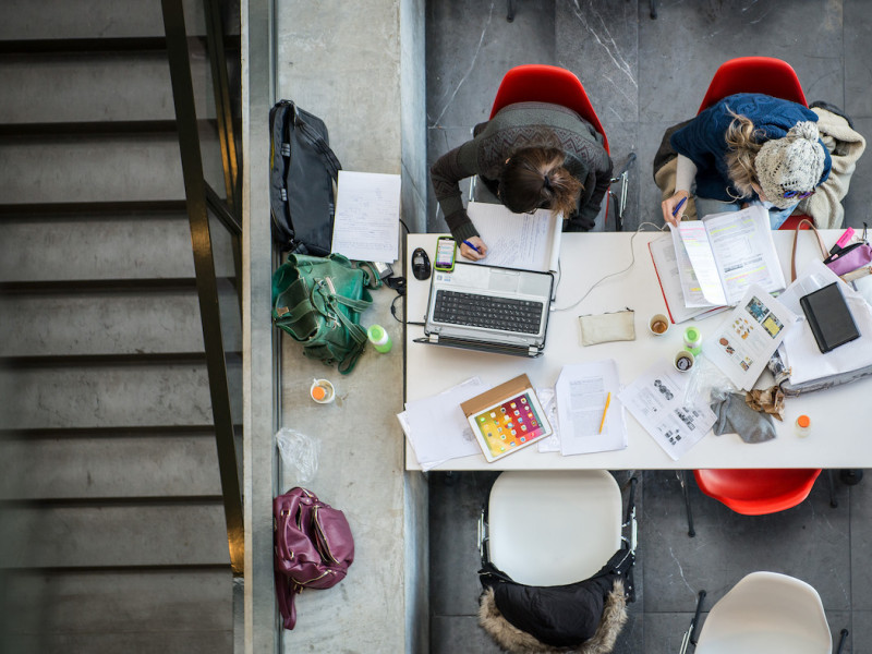 Studenten aan een tafel achter hun laptops