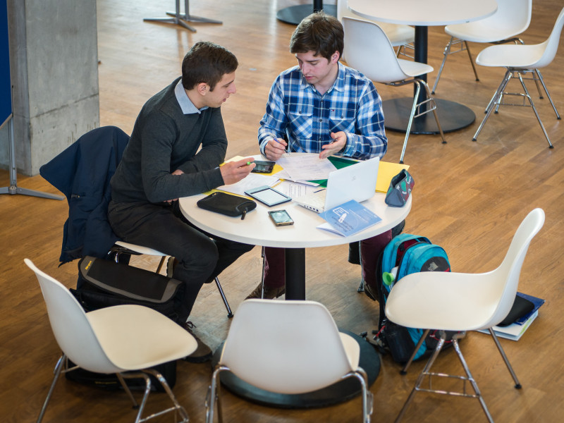 Studenten aan tafel met verschillende devices