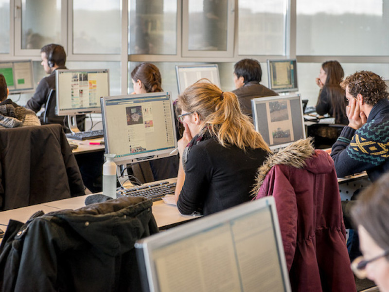 Tientallen mensen in ruimte achter computer