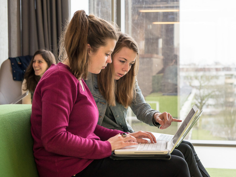 Twee studentes kijken samen naar een laptop