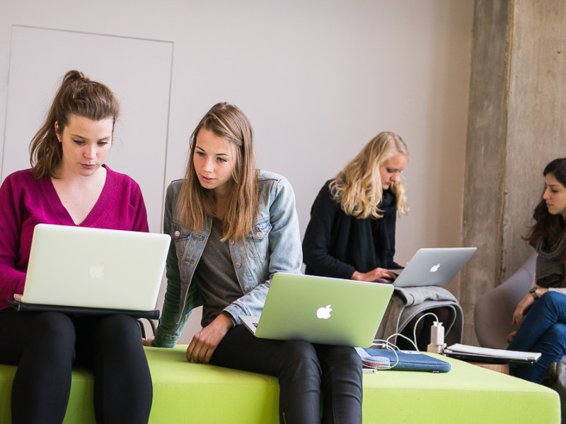 Twee studentes met laptop op schoot op een bankje