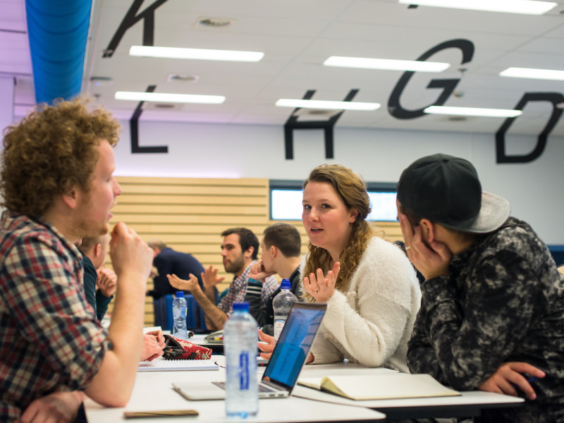 Studenten in gesprek aan tafel met laptop