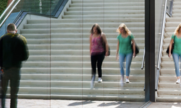 Studentes die buiten van een trap naast spiegelend glas