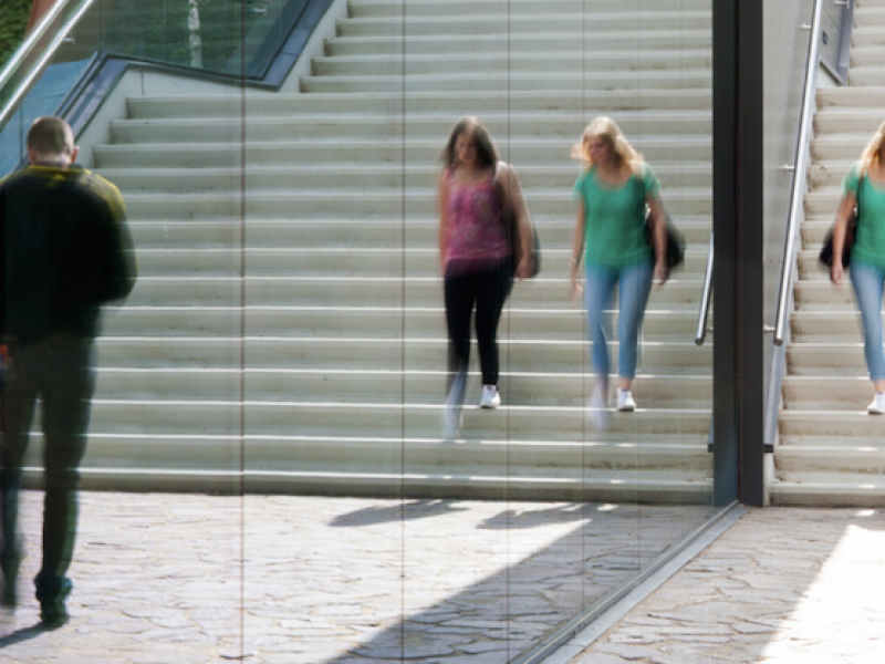 Studentes die buiten van een trap naast spiegelend glas