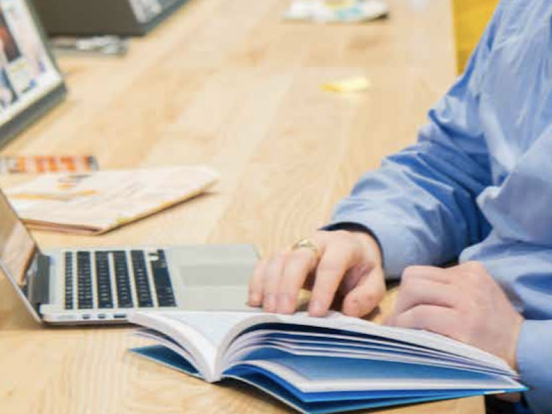 Man met laptop en handboek