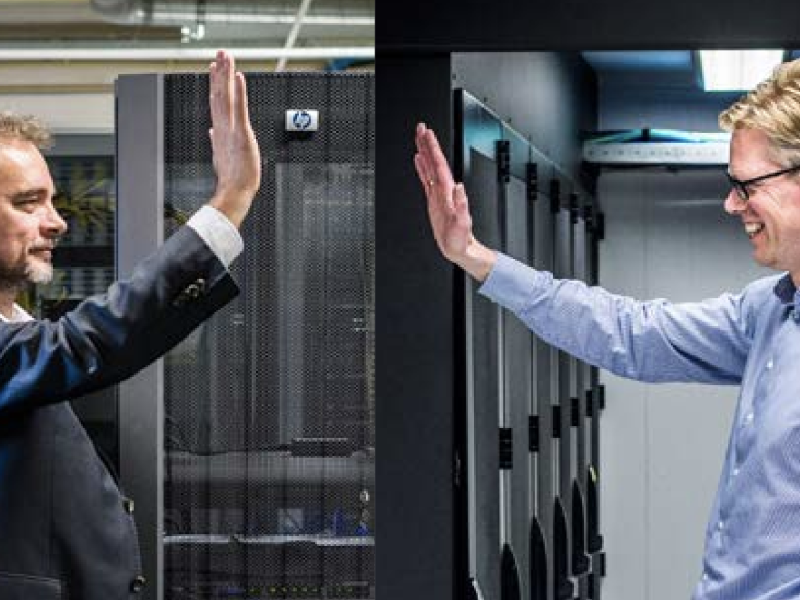 Twee mannen die elkaar een high five geven met datacentrum op de achtergrond