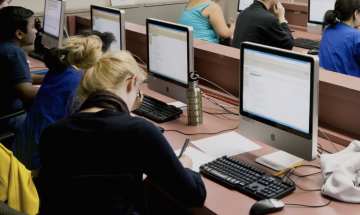 Studenten in collegezaal achter computers