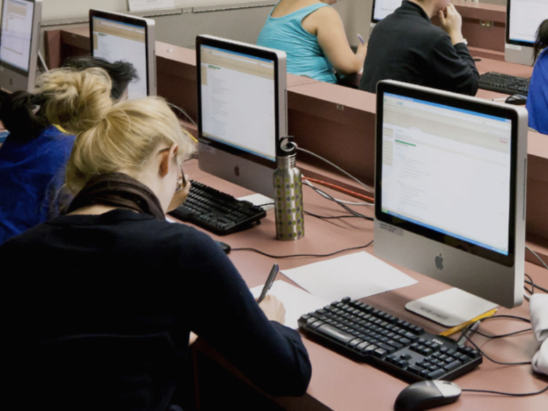 Studenten in collegezaal achter computers