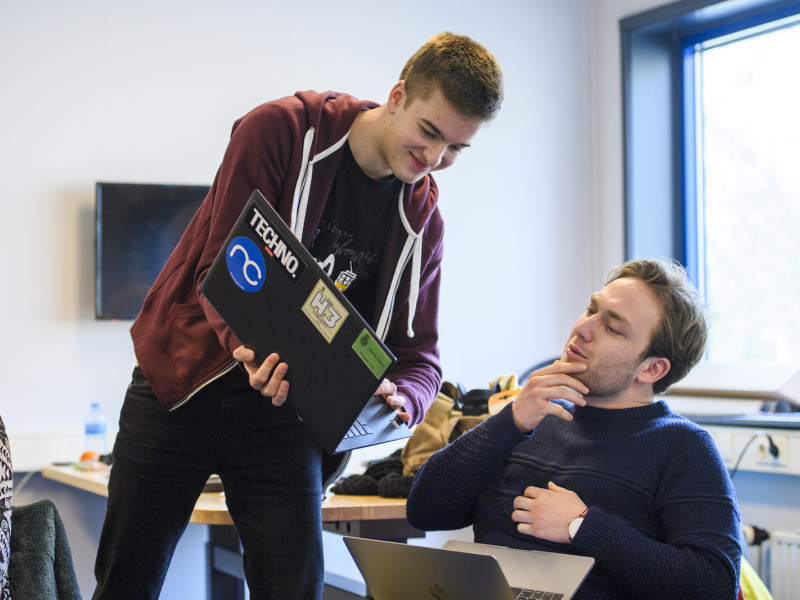 Een student die een andere student iets laat zien op zijn laptop