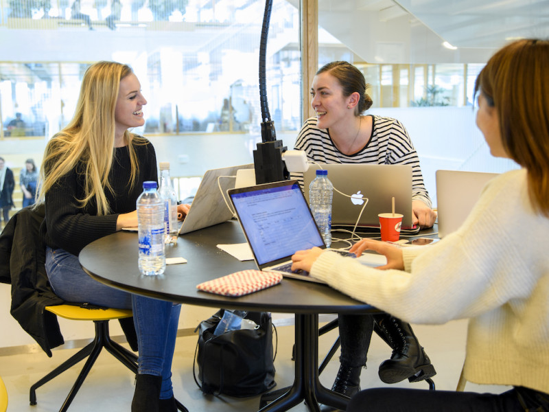 Drie studenten discussieren met elkaar aan tafel