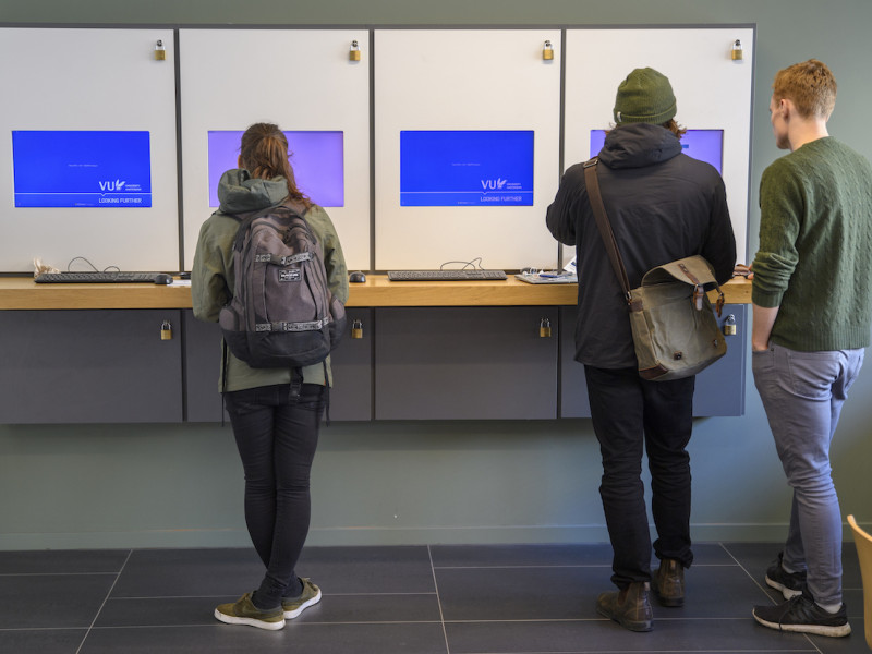 Leerlingen achter inlogwand met schermen