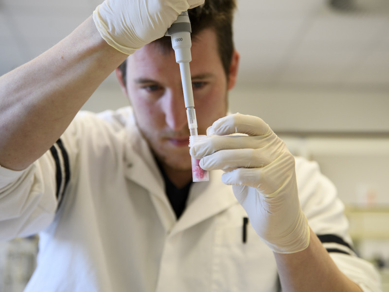 Een onderzoeker met een reageerbuis die een test uitvoert