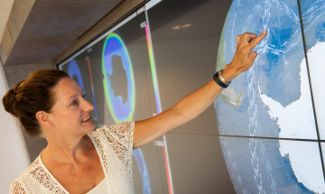 Vrouw wijst op scherm met visualisatie van zeestromingen