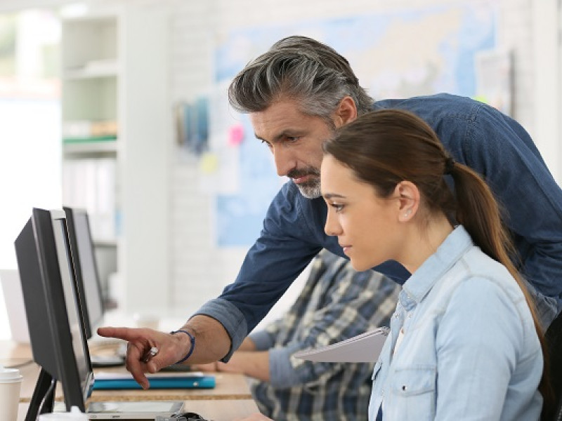 Man en vrouw achter de computer, man wijst iets aan op het scherm