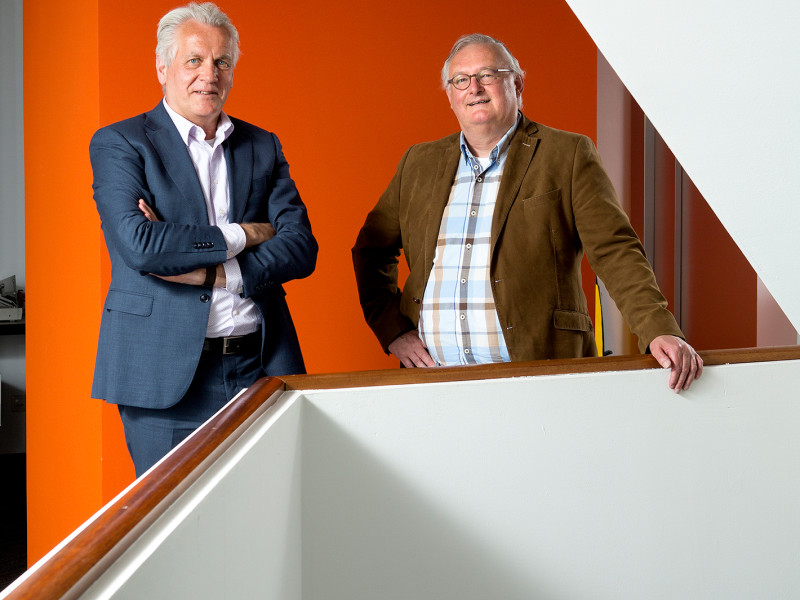 mannen in pak staan voor een oranje muur