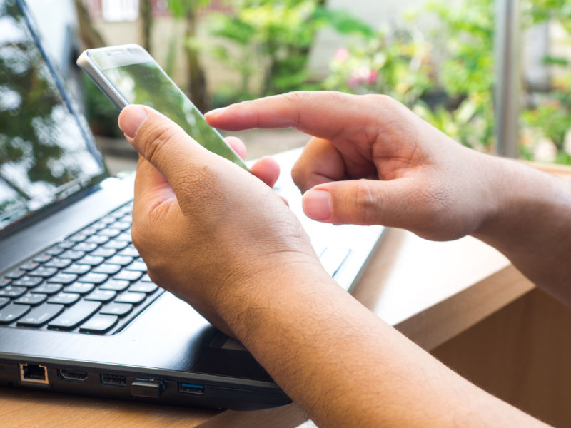 Twee handen met telefoon en laptop