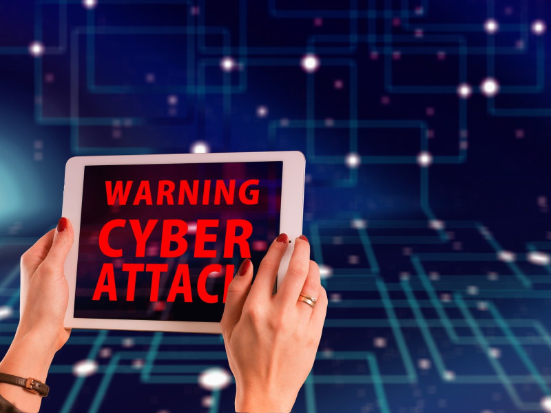 Een vrouw houdteen tablet vast met daarop de tekst 'Warning cyber attack' 