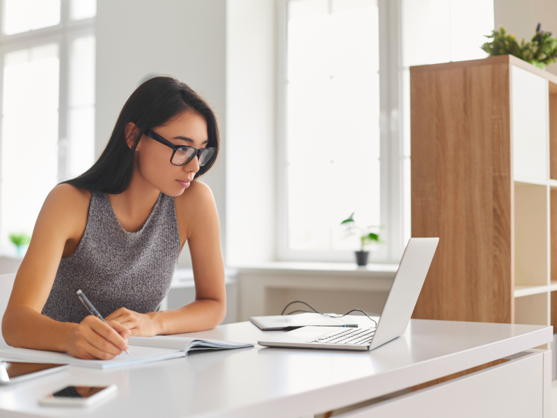 Bright Student Taking Notes in Notebook and Using Laptop Computer for E-Learning