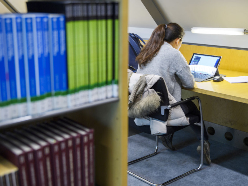 Studente werkt op laptop in bibliotheek