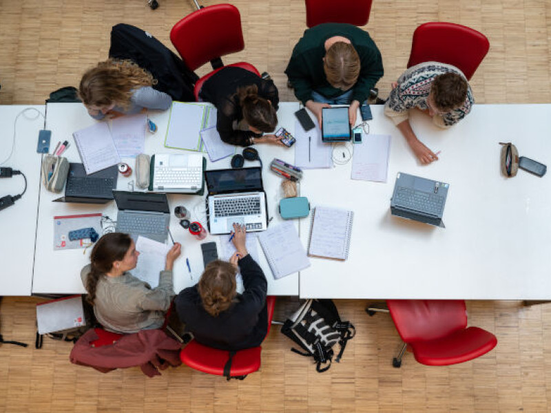 Bovenaanzicht van 6 studenten die samen studeren aan een lange tafel