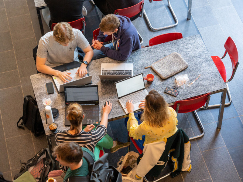 Bovenaanzicht werkplekken op de UVA met studenten