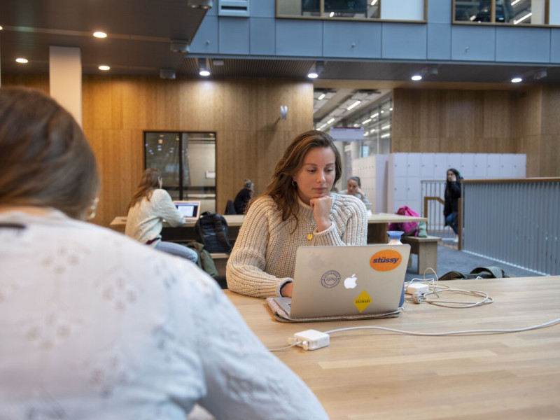 Studente op laptop aan het werk in de hal van de VU
