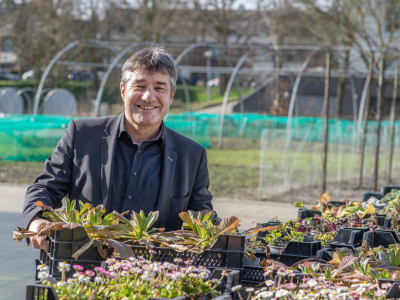 Patrick Cramers heeft een bak planten in zijn handen en lacht in de camera