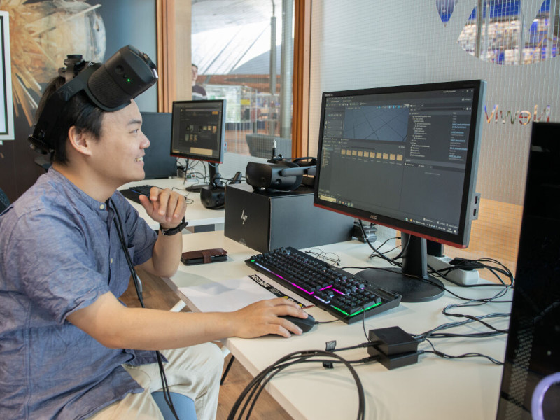 Man kijkt naar beeldscherm met VR-bril op zijn voorhoofd