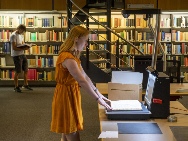 onderzoeker scant boek in bij het Internationaal Instituut voor Sociale Geschiedenis in Amsterdam