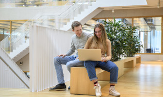 Twee studenten in een open hal met een laptop