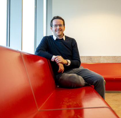 Tom Emery zit en kijkt lachend de camera in