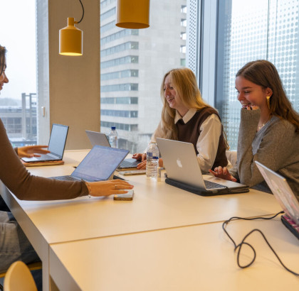 drie studenten studeren achter hun laptop aan tafel